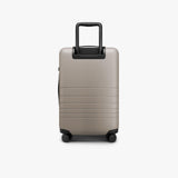 Monos Carry - On Pro Plus Luggage (23"), Hardside Spinner Suitcase with TSA Lock & Front Pocket, Airline Approved, Desert Taupe, Beige
